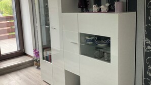A modern room with a large wardrobe, a glass cabinet, and a window with a view of the outdoors.