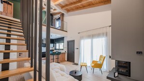 A modern living room with a sofa, a coffee table, and a fireplace. There is a staircase leading to an upper level. - Rosy pair,private pool & jacuzzi near waterpark & Beach (Anopolis)