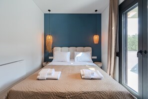A modern hotel room with a large bed, two bedside tables, a window with curtains, and a view of the outdoors.