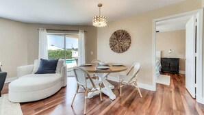 Un salon moderne avec une table à manger ronde, un canapé blanc et un grand élément décoratif mural.