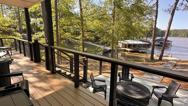 A wooden deck with outdoor seating, overlooking a lake with a dock and a covered area.