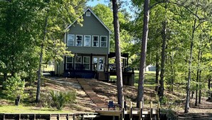 A house with a dock extending into a lake, surrounded by trees.
