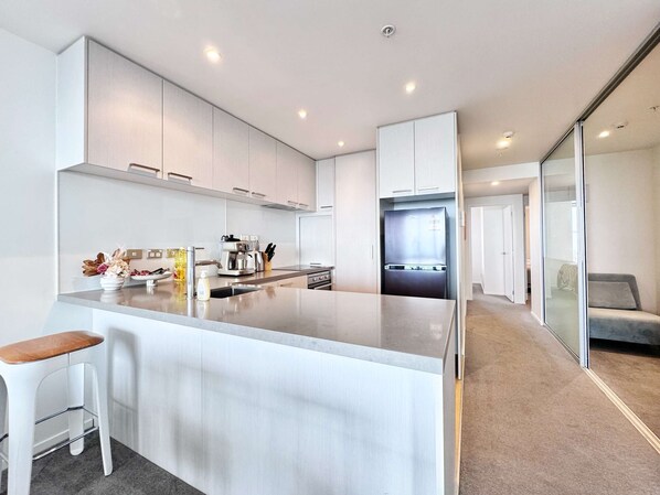 A modern kitchen with a central island, white cabinetry, and a built-in refrigerator.