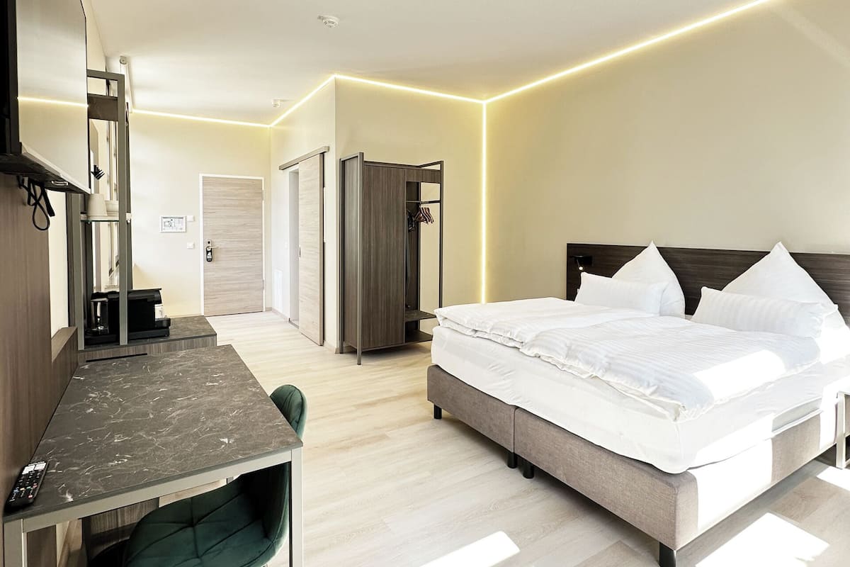 A modern hotel room with a bed, desk, and chair.