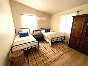 Two single beds with matching headboards and footboards, a wooden wardrobe, and a wicker basket.