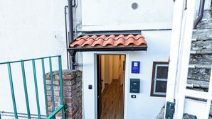 A white building with a red-tiled roof, a wooden door, and a small window. - BELLAVISTA APARTMENT (Blevio)