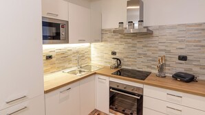 A modern kitchen with a built-in microwave, stainless steel range hood, and a dishwasher. - BELLAVISTA APARTMENT (Blevio)