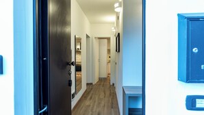 A hallway with wooden flooring, white walls, and a black door. - BELLAVISTA APARTMENT (Blevio)