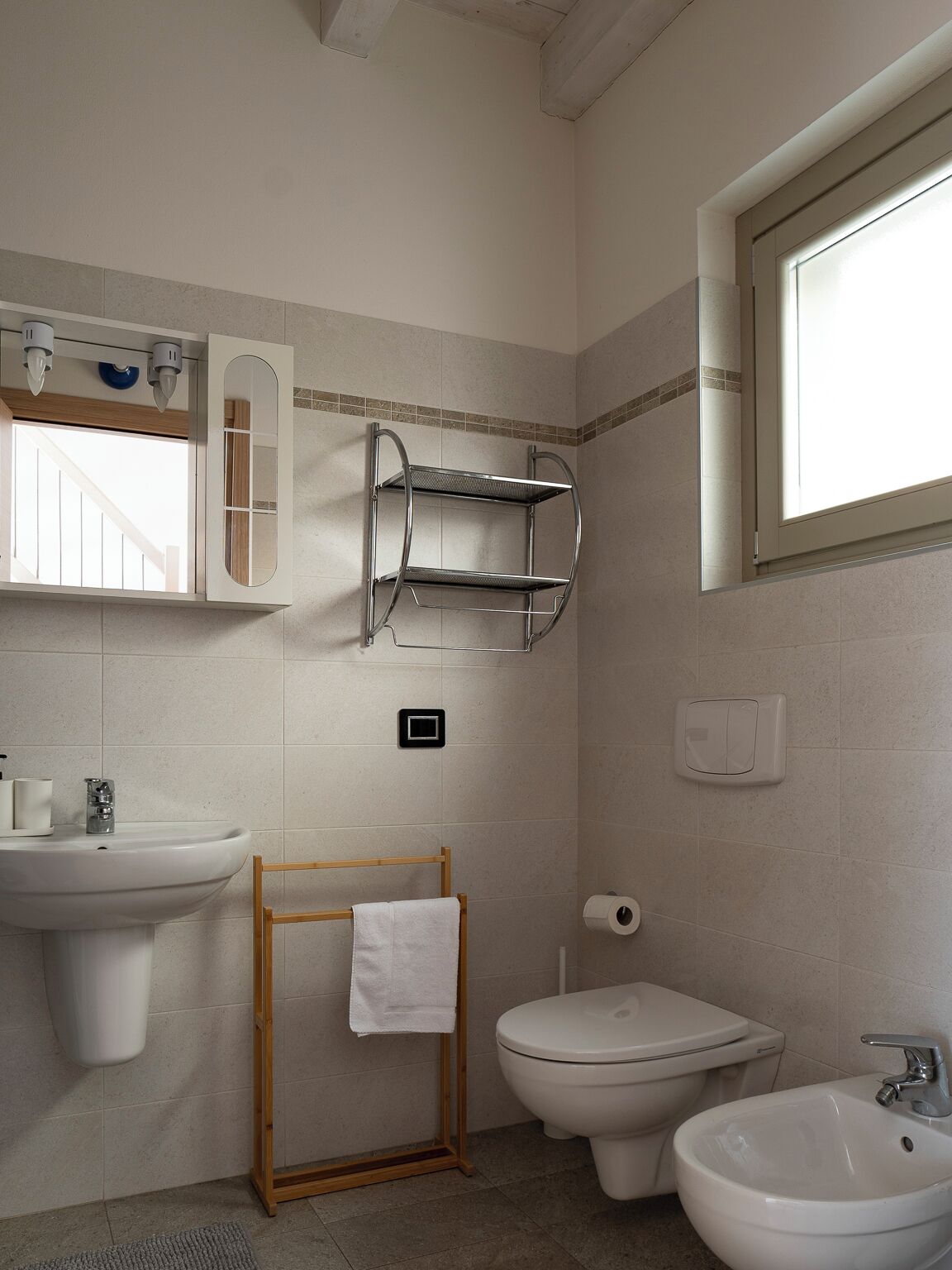 Une salle de bain équipée d’un lavabo, d’un bidet et d’un abattant pour bidet, d’un porte-serviettes et d’une fenêtre.