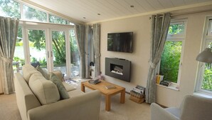 Een woonkamer met een bank, een bijzettafeltje, een aan de muur bevestigde televisie en een open haard.