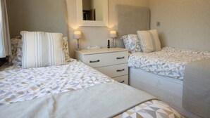 Una habitación de hotel con dos camas, un aparador y un espejo.