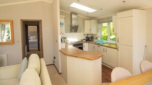 Un espacio habitable compacto con kitchenette, un comedor con mesa de madera y un sofá.