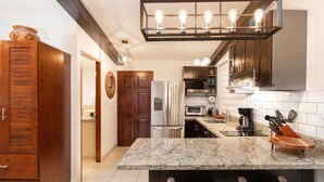 Una cocina moderna con encimeras de granito, electrodomésticos de acero inoxidable y armarios de madera oscura.