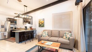Una cocina moderna con una isla central, un comedor y una sala de estar con sofá y mesa de centro.
