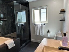 Un baño moderno con ducha de vidrio, bañera y tocador con espejo.