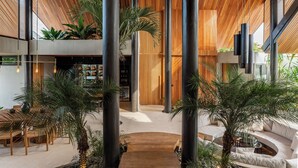 A spacious interior with a high ceiling, wooden slats, and large black columns.