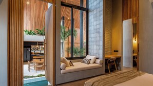 A modern bedroom with a large window, a built-in seating area, and a view of the outdoor space.