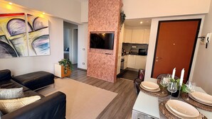 Ein modernes Wohnzimmer mit einem schwarzen Ledersofa, einem flachbildfernseher an einer rosa Wand und abstrakter Kunst.