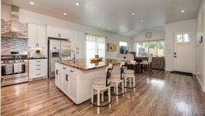 A spacious kitchen with white cabinets, a large island, and a dining area with bar stools.