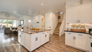 A spacious kitchen with a large island, white cabinetry, and a wooden floor.