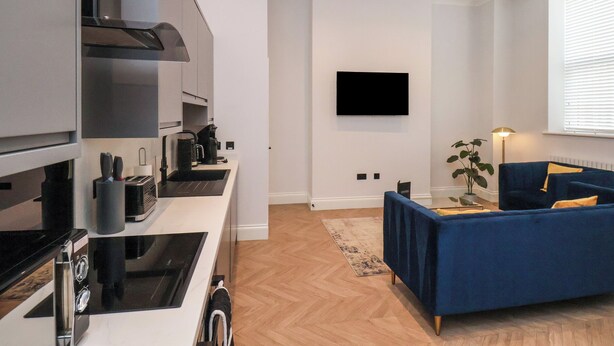 A modern kitchen with a built-in stove and a flat-screen TV mounted on the wall. - The Salisbury Apartment 103 (Scarborough)