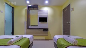 A hotel room with two beds, a TV, a mirror, and a door. - HOTEL GEMINI (Mumbai)