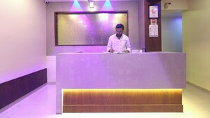 A reception desk with a modern design, a ceiling fan, and a wall-mounted light fixture. - HOTEL GEMINI (Mumbai)