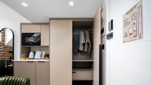 A modern, compact living space with a kitchenette, a seating area, and a closet with hanging clothes. - Your Apartment - Camden  (London)