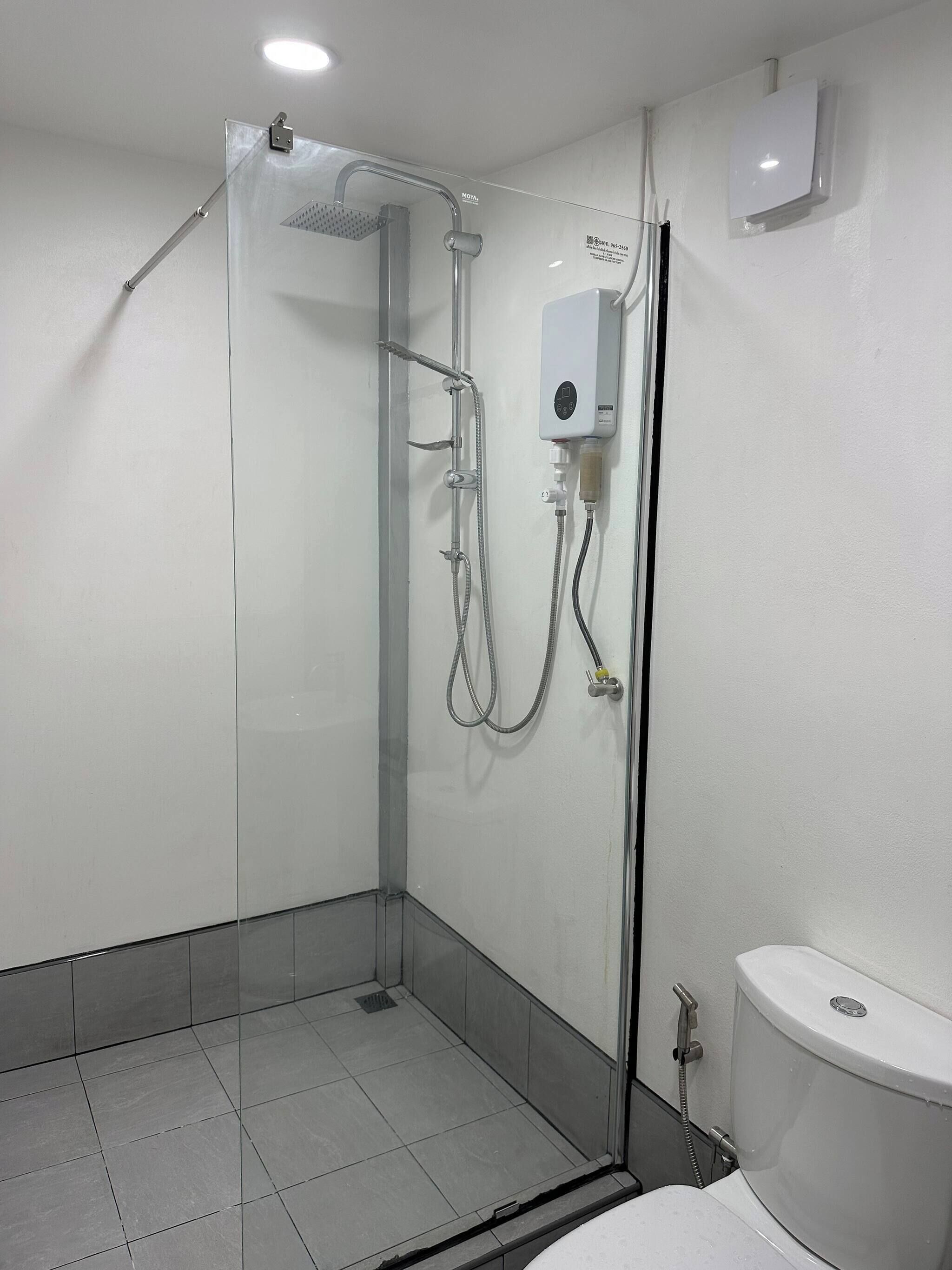 Ein modernes Badezimmer mit einer Glaskabinentrennung zur Dusche, einer Toilette und einem Wandheizkörper.