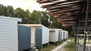 En rad med flyttbara stugor, med en asfalterad gångväg som leder fram till dem, omgivna av grönska.