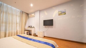 A hotel room with a bed, a desk, and a television mounted on the wall.
