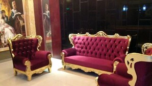 A luxurious room with two ornate, gold-trimmed, purple velvet sofas and a matching armchair.