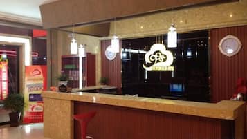 A reception desk with a neon sign, a mirror above it, and a red chair.