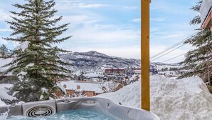 A hot tub with a snowy mountain view, surrounded by snow. - Victorian Under the Gondola: 1 Bedroom Apartment (Steamboat Springs)