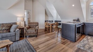 A loft-style living space with a dining area, kitchen, and a high ceiling with a fan. - Victorian Under the Gondola: 1 Bedroom Apartment (Steamboat Springs)