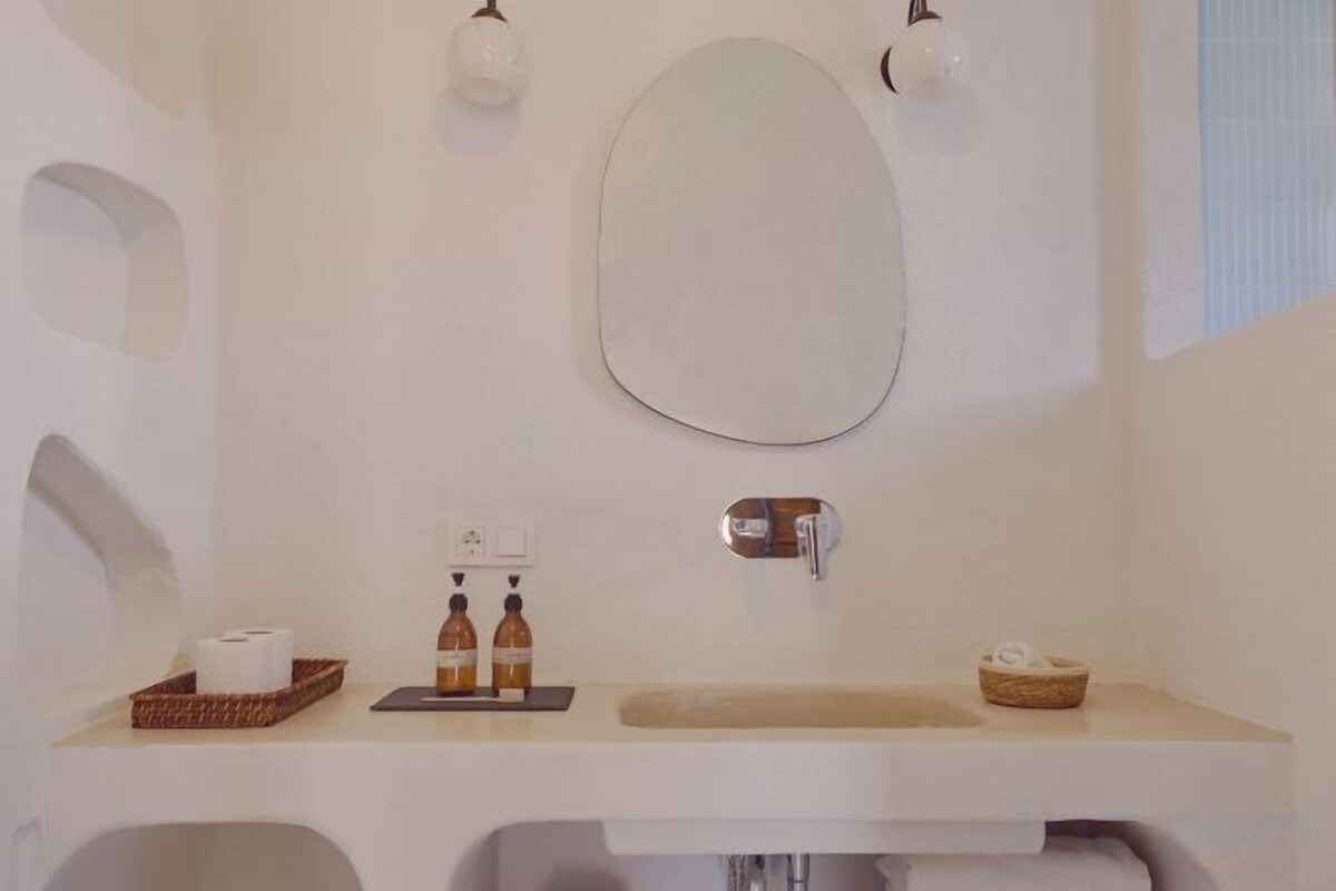 A bathroom with a large mirror, a sink, and a towel rack.