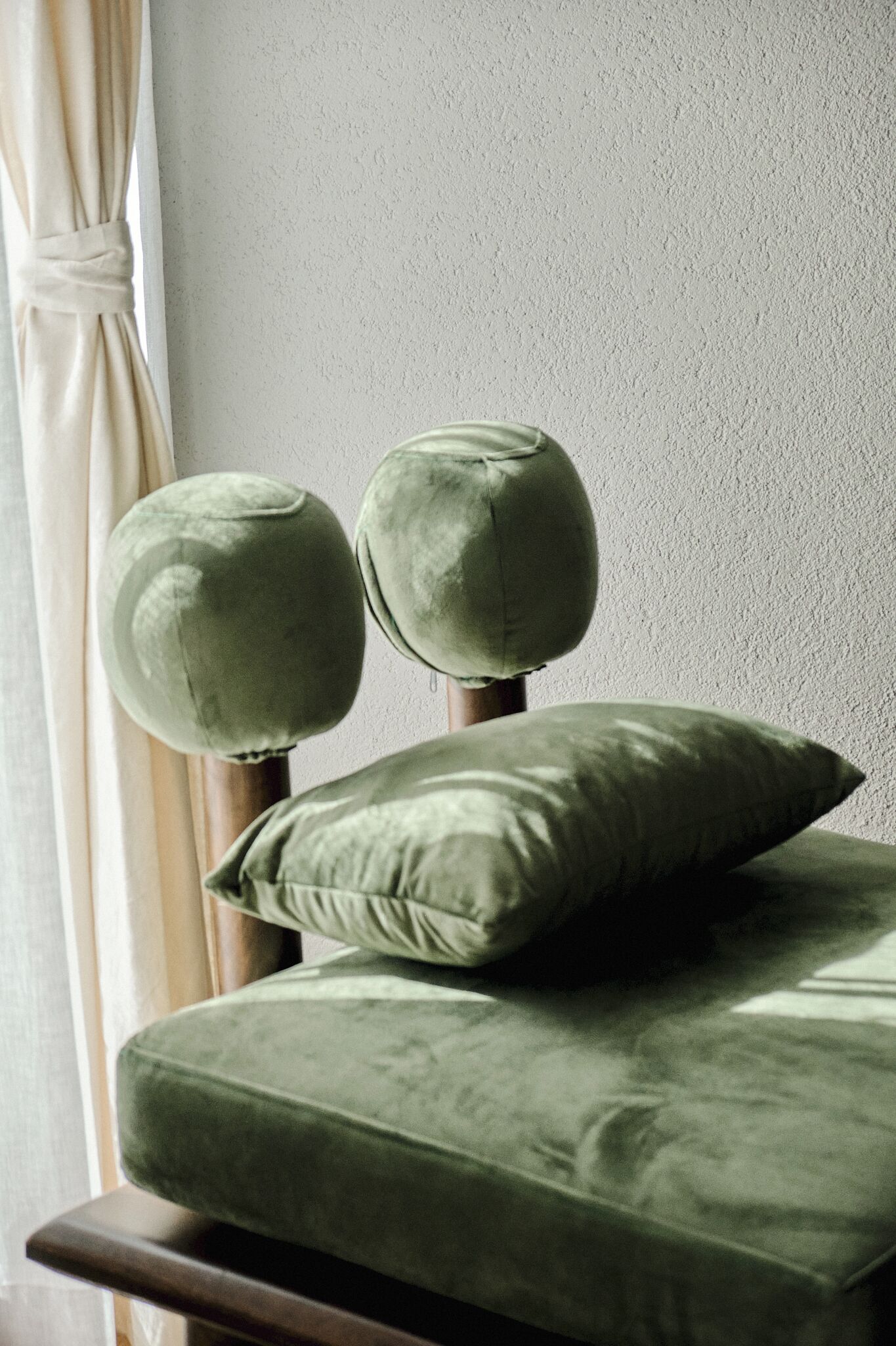 A bed with a green upholstered headboard and a matching pillow.