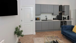 A modern kitchen with grey cabinets, a black range hood, and a built-in oven.