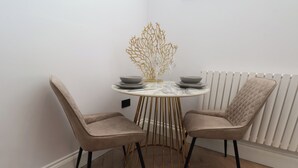 A dining area with a round table, two chairs, a decorative golden tree, and a white radiator.