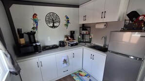 A compact kitchen with white cabinets, a stainless steel refrigerator, and a colorful rug.