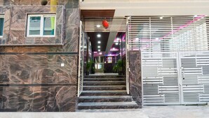 Una escalera conduce a la entrada de un edificio, con una puerta de seguridad, paredes de mármol y una decoración de pájaro rojo.