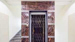 Una escalera que lleva a una puerta con reja metálica, paredes de mármol y un diseño de mármol rojo y negro.