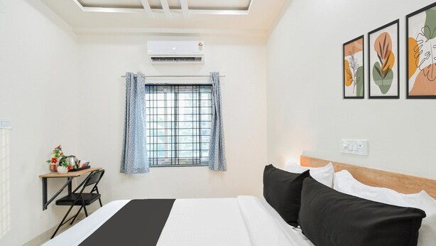Una habitación de hotel con cama, un escritorio con silla, ventana con cortinas y decoración en la pared.