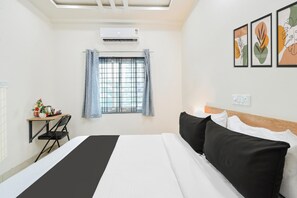 Una habitación de hotel con cama, un escritorio con silla, ventana con cortinas y decoración en la pared.