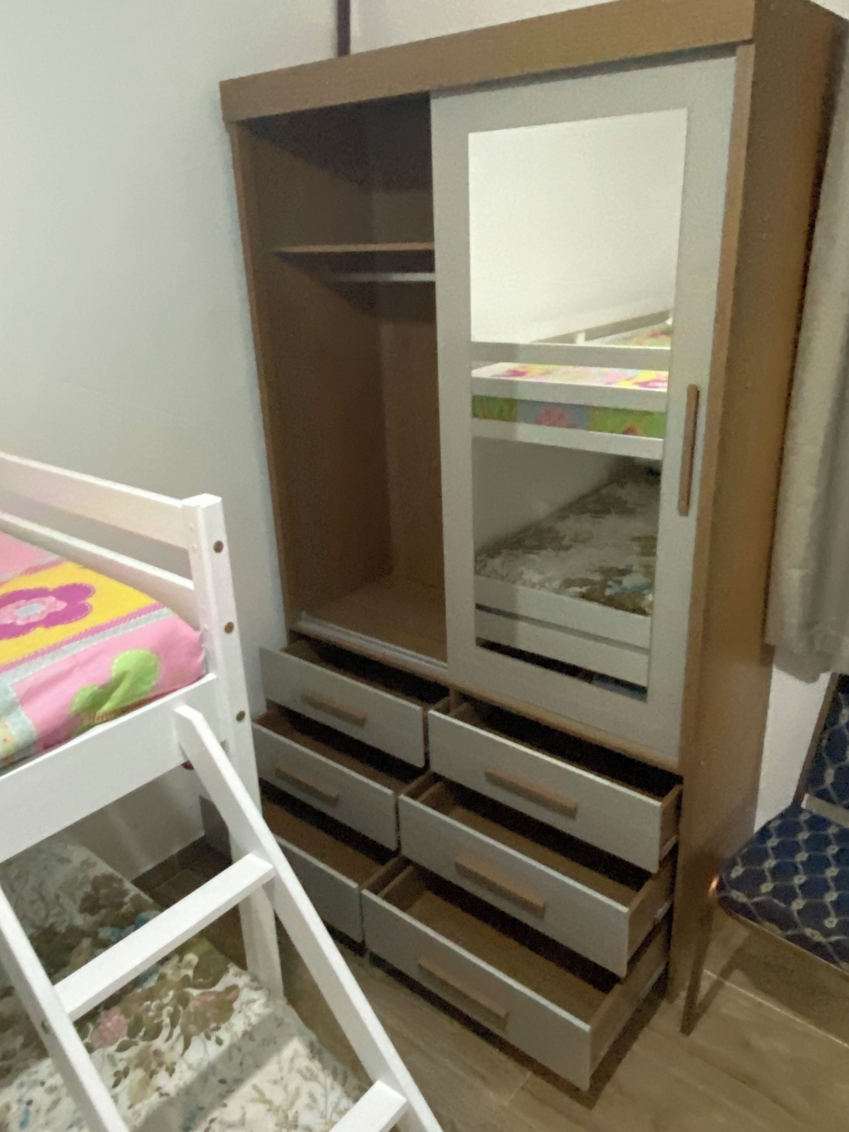 Une chambre avec un lit superposé, une armoire avec plusieurs tiroirs et une chaise.