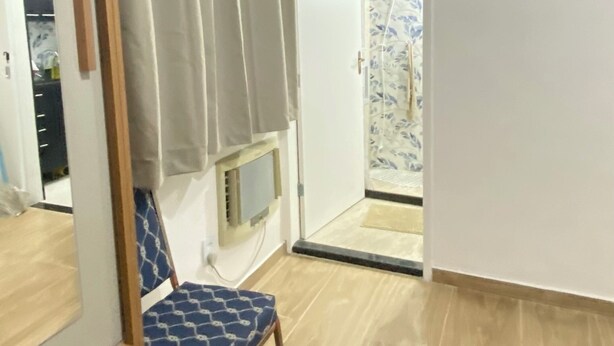A room with a wooden floor, a blue patterned chair, and a white door with a curtain. - Lapa the Bohemian Neighborhood of Rio. The Wonderful City with Comfort and Safety. (Centro Rio de Janeiro)