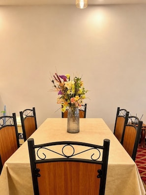 Une table à manger ornée d’un vase de fleurs, entourée de chaises.