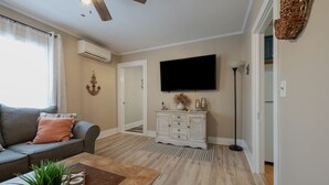 Una sala de estar con sofá, mesa de centro, televisor, aparador y ventilador de techo.