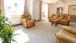 A spacious living room with a large window, a fireplace, and a bookshelf. - Cedar View (Norwich)