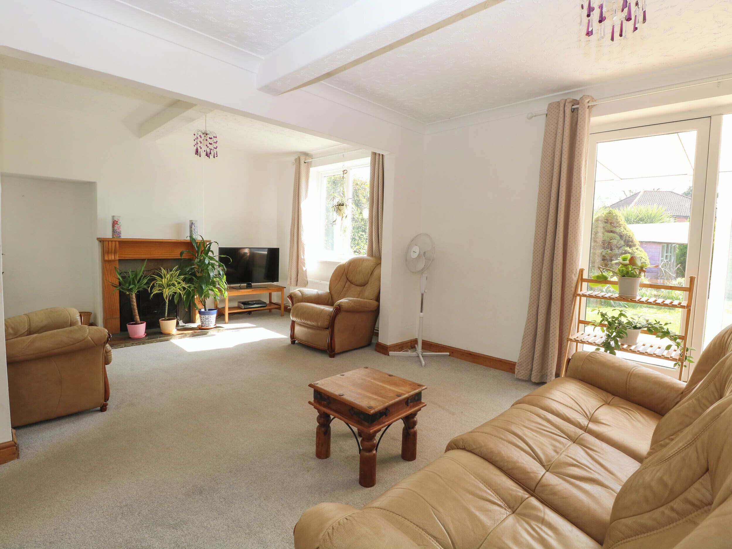 A living room with a sofa set, a television, a fireplace, and a window with curtains.
